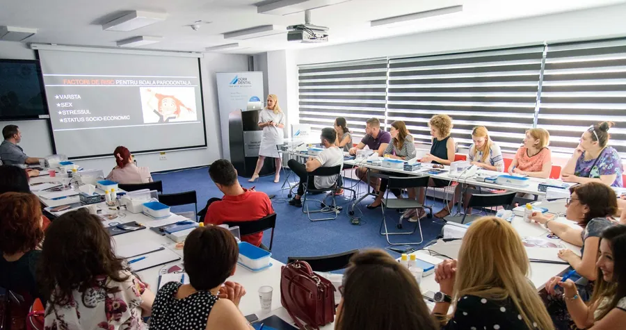 Un curs SSER: participanți la mese lungi, în fața ecranului.
